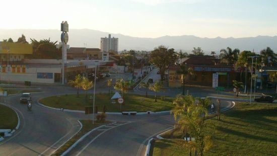 rotatória da entrada da cidade de Lorena com uma grande área verde ao centro e lojas na beira da avenida