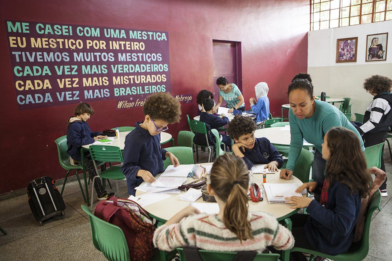 Alunos trabalham em grupo com a ajuda de uma professora tutora na escola Desembargador Amorim Lima, em São Paulo