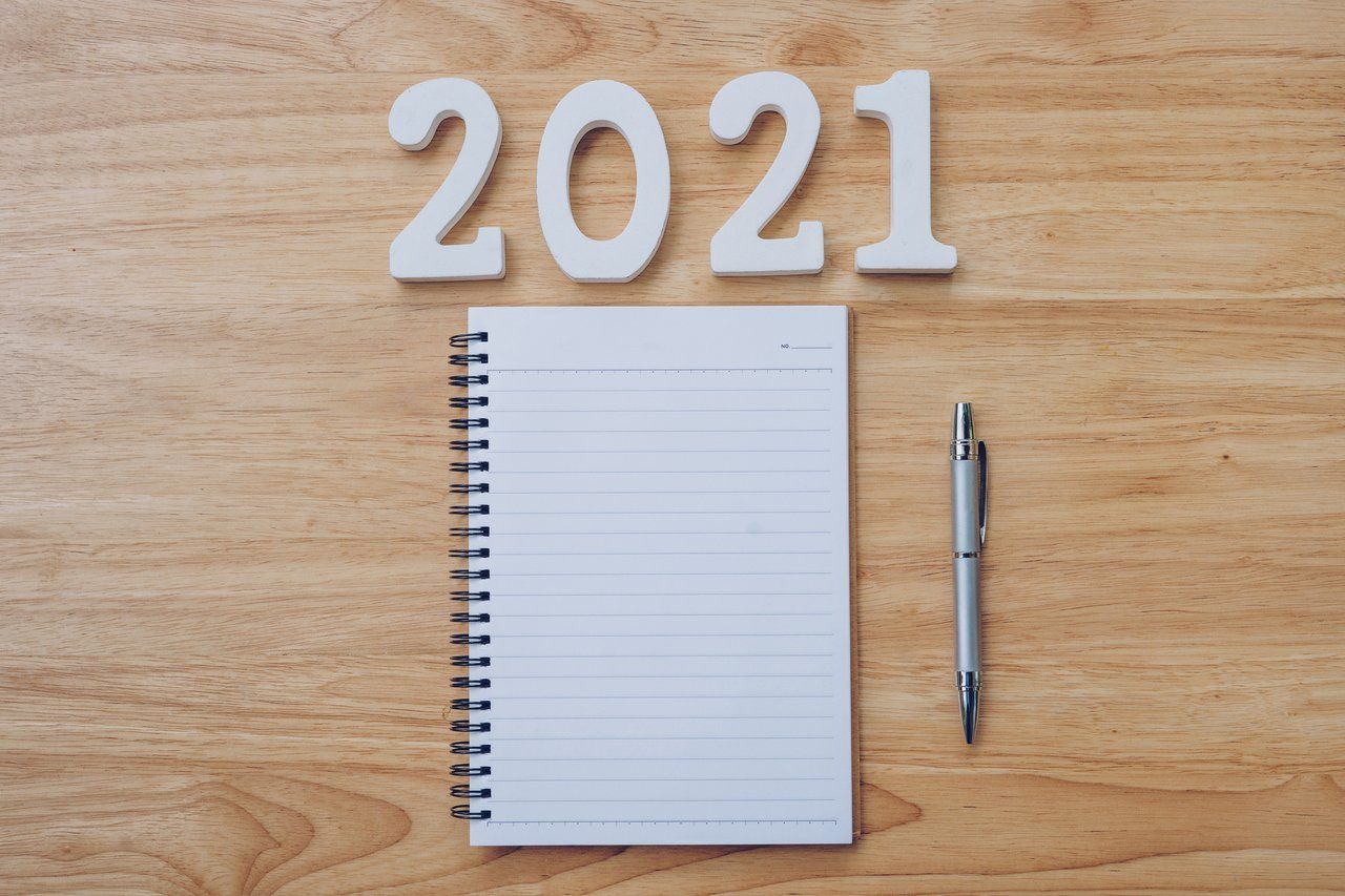 Caderno em branco sob uma mesa de escritório. Acima no letreiro escrito 2021