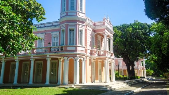 Prédio clássico de fachada rosa com detalhes brancos e entrada em L