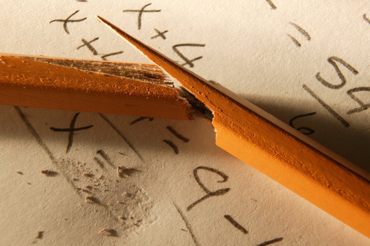 Lápis quebrado em caderno com operações matemáticas