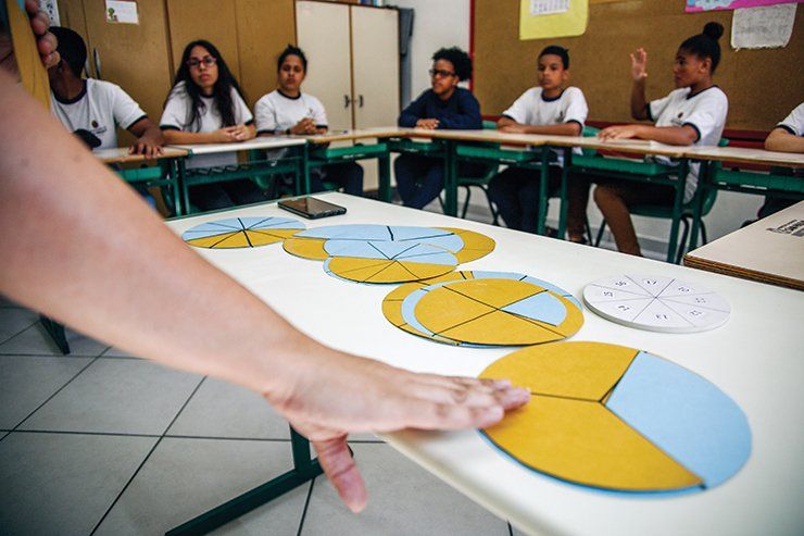 jovem professora ensinando aula de matemática para alunos na sala