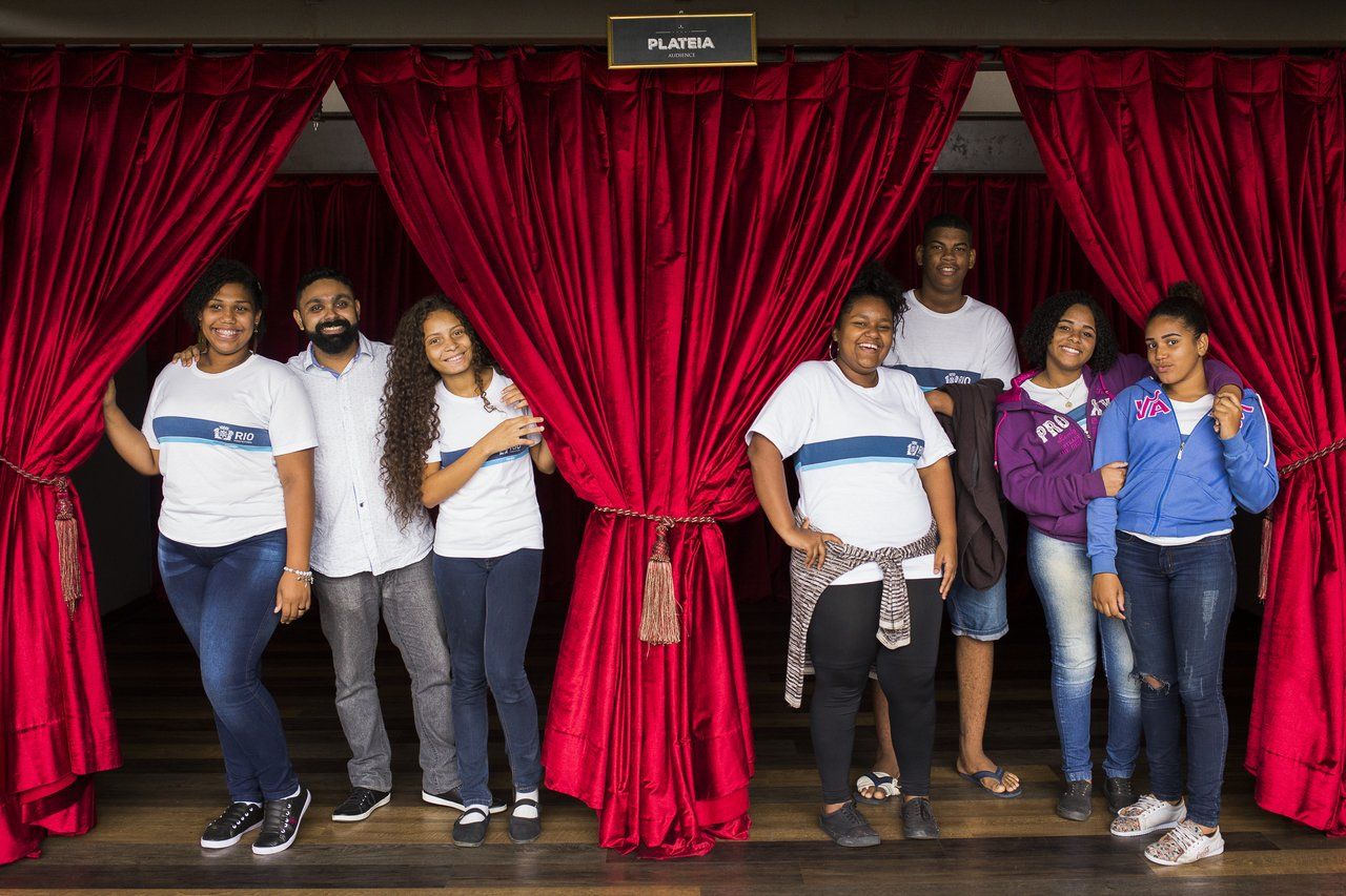 Professor José Marcos Couto Júnior e os alunos do Projeto As Caravanas: Limites da Visibilidade, em um palco de teatro no Rio de Janeiro, brincando com as cortinas