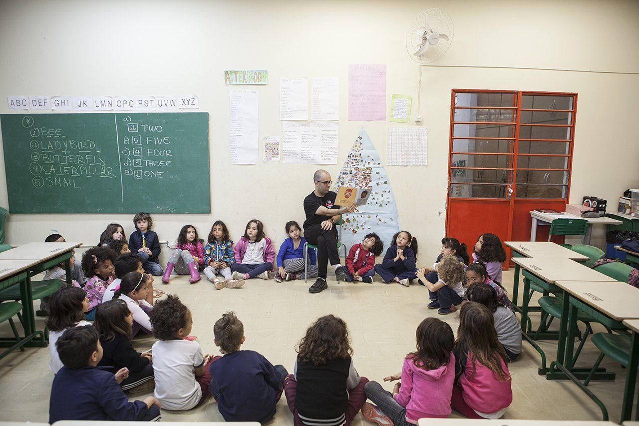 Alunos da escola municipal Desembargador Amorim Lima sentados em círculo ouvem uma história