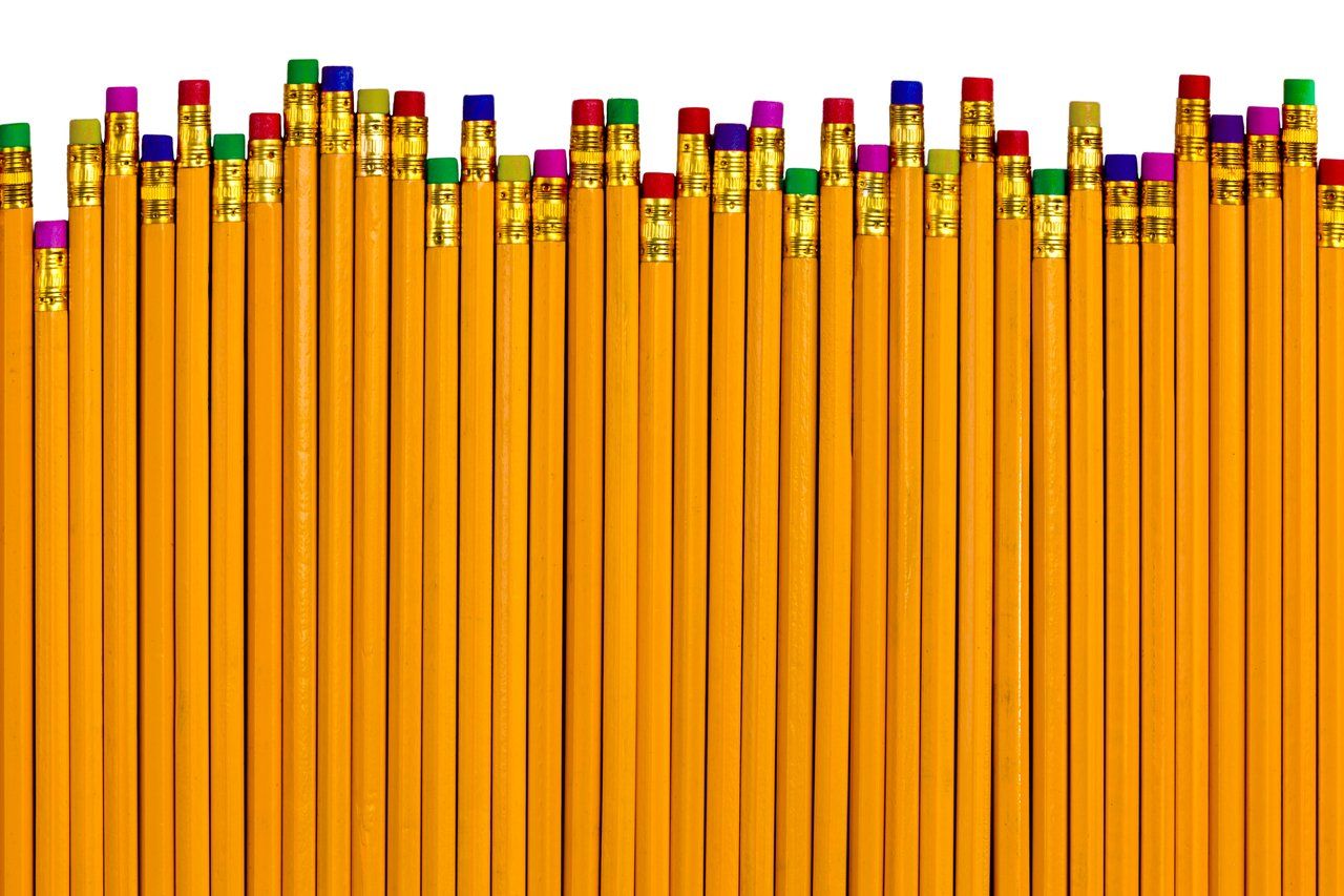 Em um fundo branco, vários lápis amarelos com borrachas de cores diferentes na ponta, estão dispostos em posições levemente diferentes